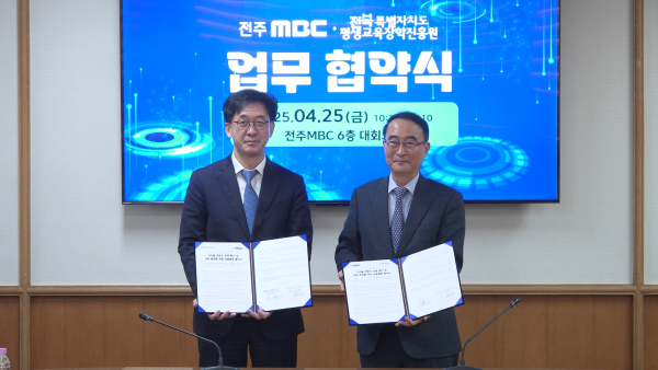 전주MBC와 전북특별자치도평생교육장학진흥원 간 업무협약식 현장. 양 기관 대표가 협약서를 들고 서 있으며, 뒤 스크린에는 “전주MBC × 전북특별자치도평생교육장학진흥원 업무협약식, 2025.04.25(금) 전주MBC 6층 대회의실” 문구가 표시되어 있다.